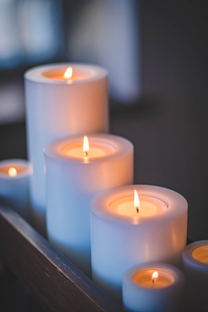 A row of five white candles are lit.