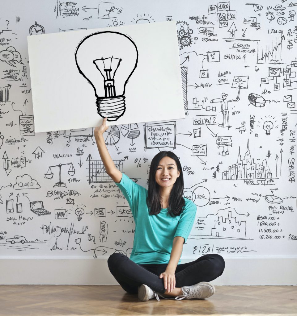 young woman holding up an image of a lightbulb representing one big idea